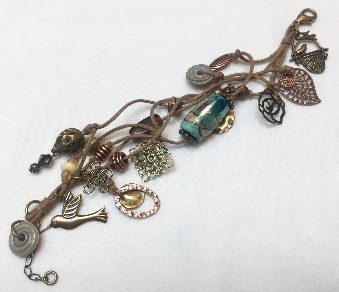 A bracelet with a bird and flower charms tied on