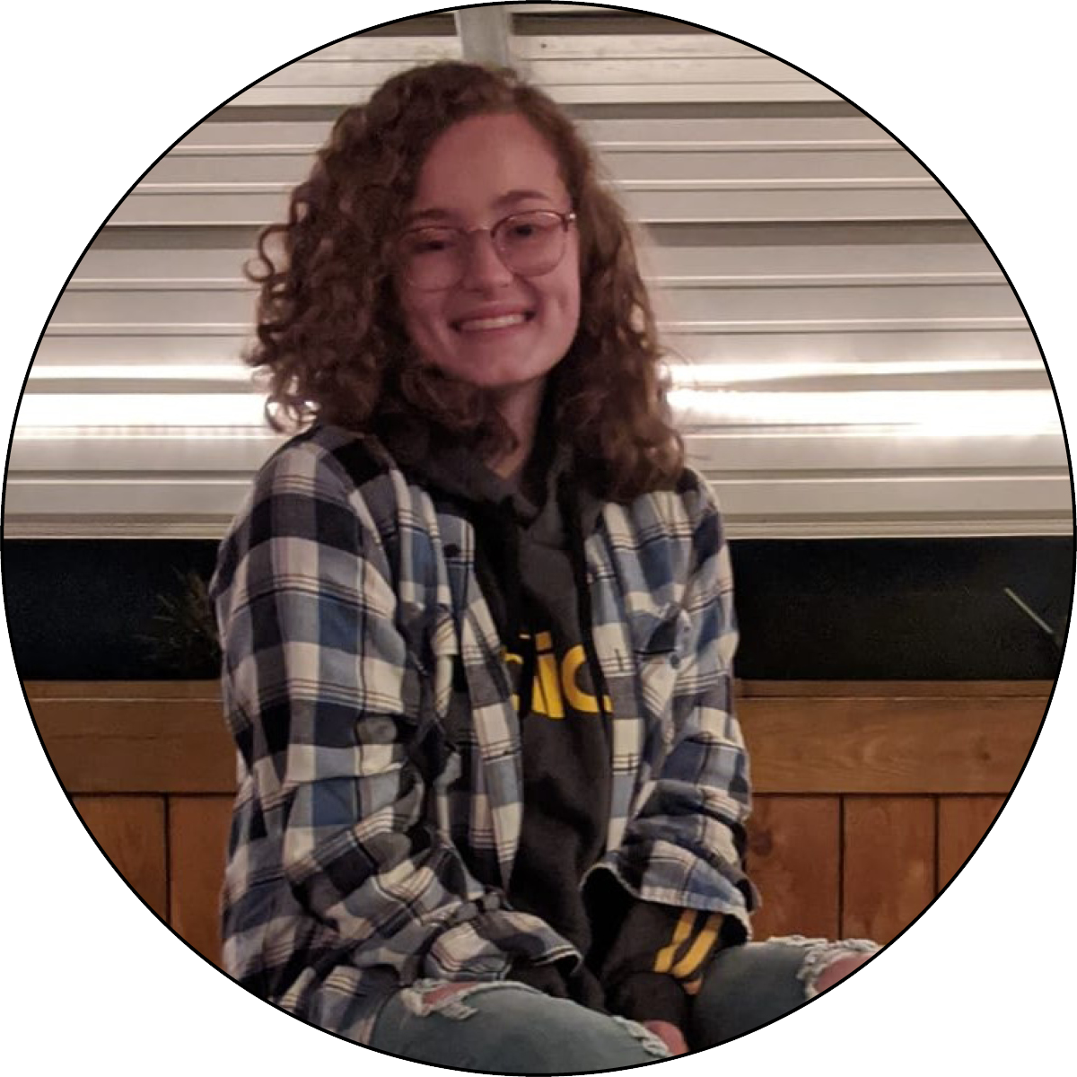 Rachael Thomas sits on the top of a table while smiling at the camera