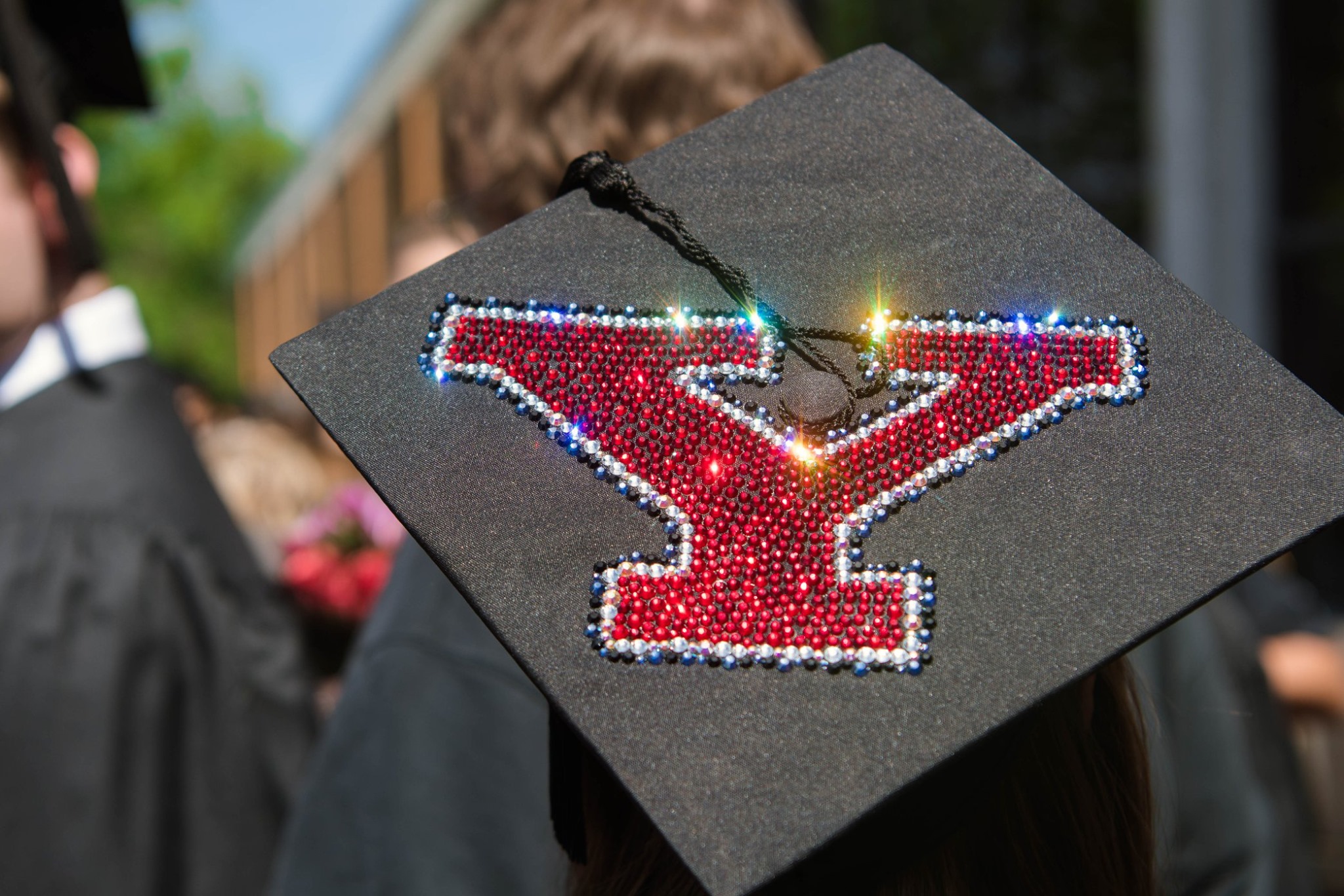 A graduation cap decorated with red rhinestones in the shape of Y.