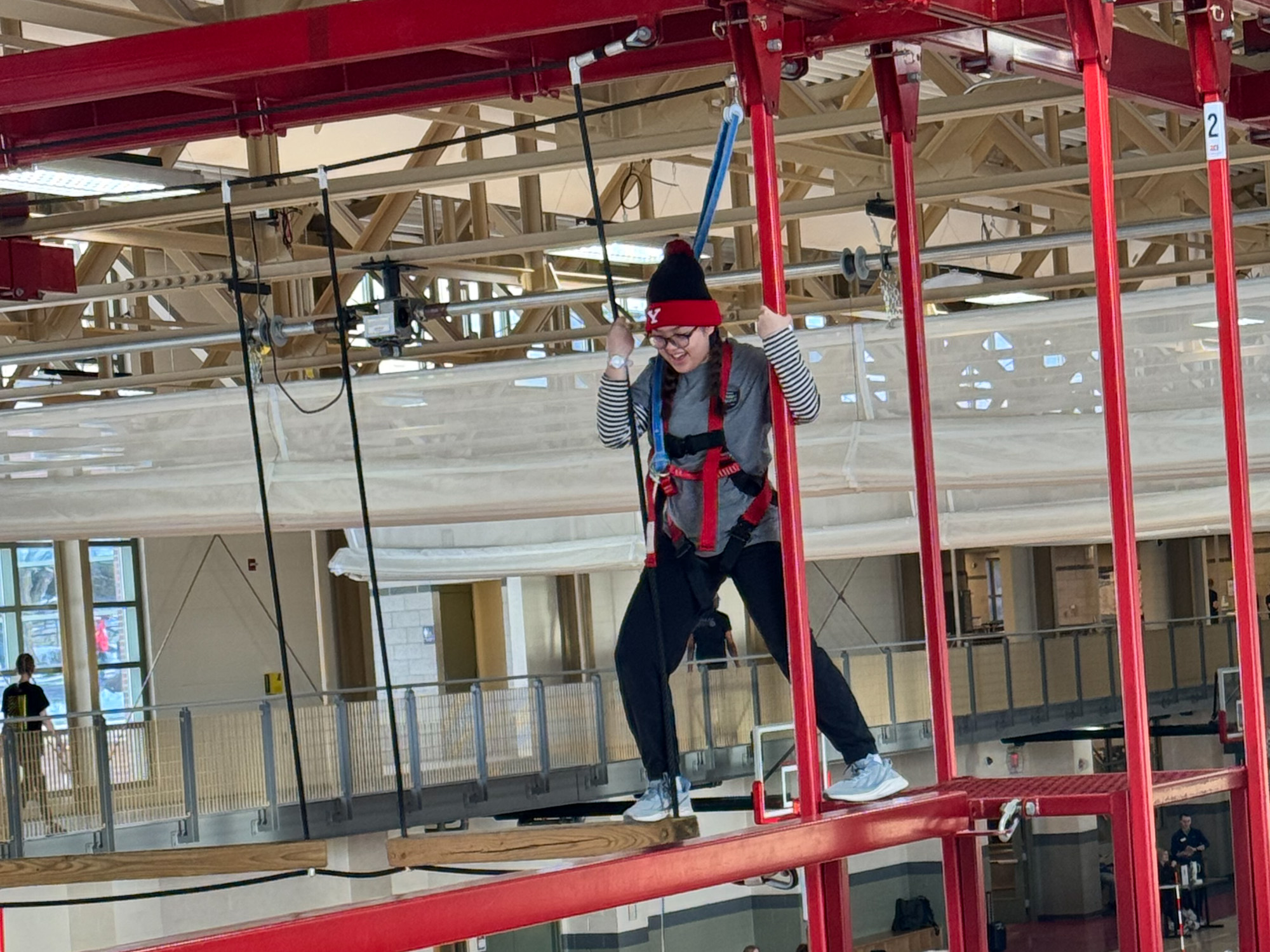 student walking across the high ropes course bridge