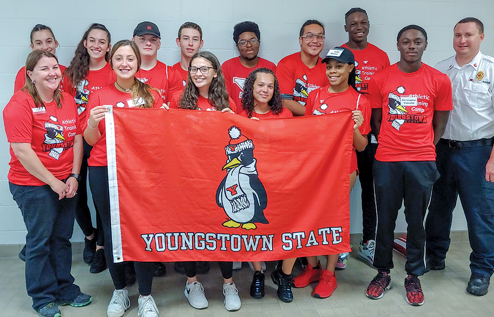 Students from the Athletic Training camp pose with a YSU flag