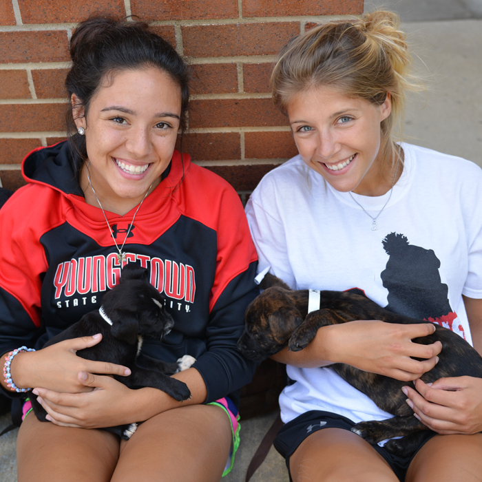 Two students holding puppies