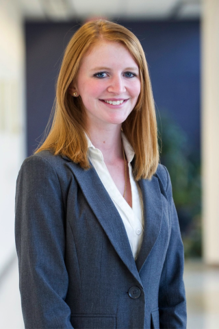 A headshot of a smiling female student wearing a grey pantsuit