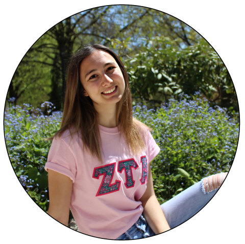 Student wearing a pink shirt with the letters Z-T-A on the front, posing outside