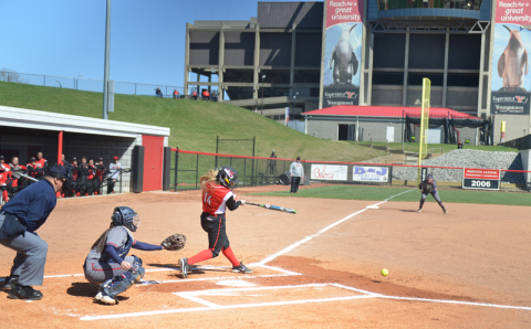 With Stambaugh Stadium towering in the distance, Penguin outfielder Sarah Dowd connects during a recent softball contest at the YSU field west of Fifth Avenue. Catch a Penguins game on campus this spring!