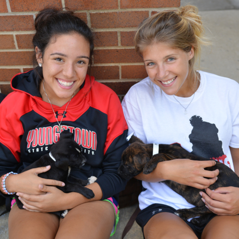 Two students holding puppies