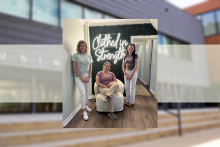 members of the Student Nonprofit Leadership Organization pose in front of the Clothed in Strength logo