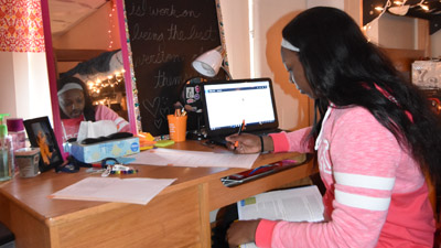 girl working on paper in her room